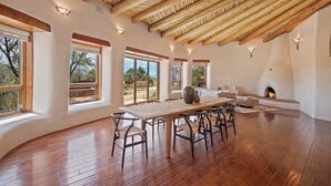 A spacious room with a wooden ceiling, large windows, a fireplace, and a dining area with chairs and a table. - Summer Pool, Hot Tub, Stunning Luxury (Santa Fe)