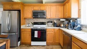 Une cuisine dotée de meubles en bois, d’appareils électroménagers en acier inoxydable, d’un four à micro-ondes, d’une cuisinière et d’un lave-vaisselle.