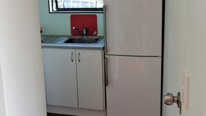 Uma cozinha compacta com pia, armários e geladeira.