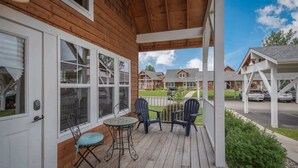Une terrasse en bois avec une table et des chaises, un porche couvert et une vue sur les maisons voisines.
