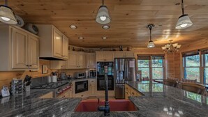 A modern kitchen with granite countertops, stainless steel appliances, and wooden cabinetry. - A perfect mountain view getaway (Ellijay)