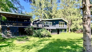Une maison à deux étages avec un porche et un grand jardin à l’avant.