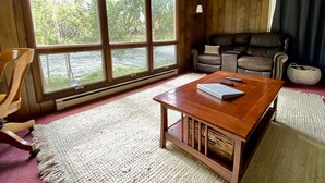 Un salon chaleureux avec une grande fenêtre, un canapé en cuir, une table basse en bois et un fauteuil.