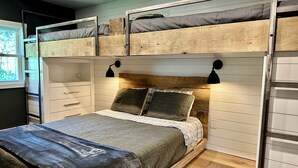 Un lit superposé avec une tête de lit en bois, une table de chevet avec des tiroirs et une lampe fixée au mur.