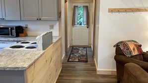 A kitchen with a built-in island, wooden cabinets, and a microwave. - Baker cabin|Downtown Greenville-Moosehead Lake|WIFI|Pets Ok|2 cabins available (Greenville)