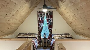 A cozy attic bedroom with two beds, a wooden ceiling, and a view of the outdoors through a window. - Baker cabin|Downtown Greenville-Moosehead Lake|WIFI|Pets Ok|2 cabins available (Greenville)