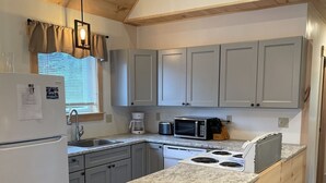 A kitchen with a central island, grey cabinets, a white refrigerator, and a wooden ceiling. - Baker cabin|Downtown Greenville-Moosehead Lake|WIFI|Pets Ok|2 cabins available (Greenville)