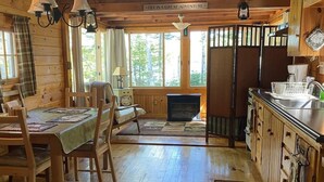 Interior acogedor de una cabaña con comedor, cocina y chimenea.