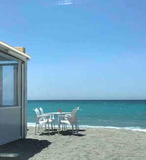 A beachside seating area with a table and chairs facing the ocean.