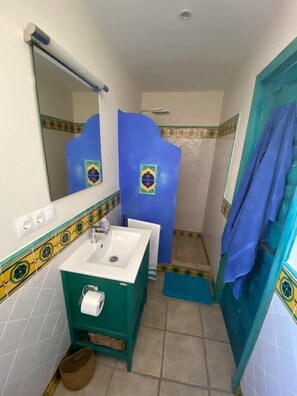 A bathroom with a white sink, green vanity, and blue shower enclosure.
