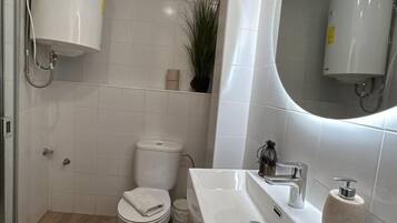 Un baño con inodoro, lavamanos y espejo.