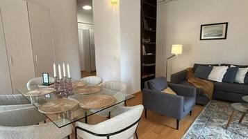 Una sala moderna con una mesa de comedor de vidrio, un sofá gris y un tapete estampado.