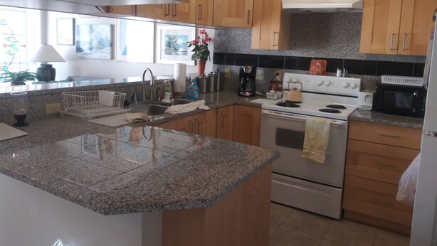 A kitchen with wooden cabinets, granite countertops, a stove, and a microwave.