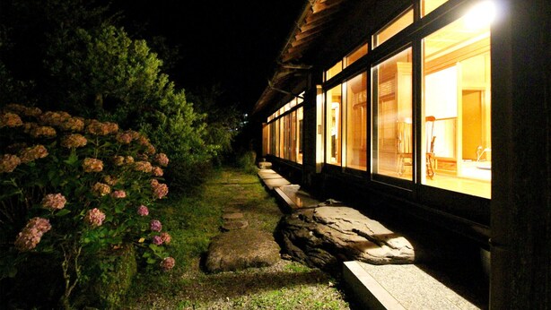 A building with large windows, a stone pathway, and pink flowers.