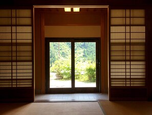 A traditional Japanese room with tatami flooring, a sliding door leading to a garden, and shoji screens on the sides. - Hoshi to Kaze no Niwa (Kamikawa)