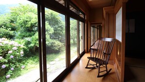 A room with large windows, a wooden floor, and a rocking chair.