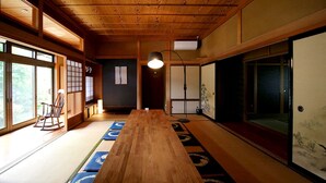 A traditional Japanese room with tatami flooring, a wooden table, sliding doors, and a view of the outdoors.