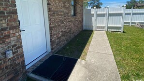 A brick building with a white door, a small window, and a white picket fence. - 1/1 Guesthouse 6mi from Beach for Perfect Getaway (Fort Walton Beach)