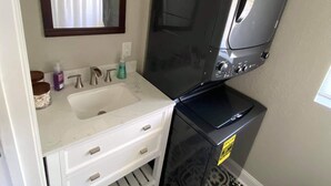 A bathroom with a white sink, a mirror, a black washing machine, patterned floor tiles, and a toilet paper holder. - 1/1 Guesthouse 6mi from Beach for Perfect Getaway (Fort Walton Beach)