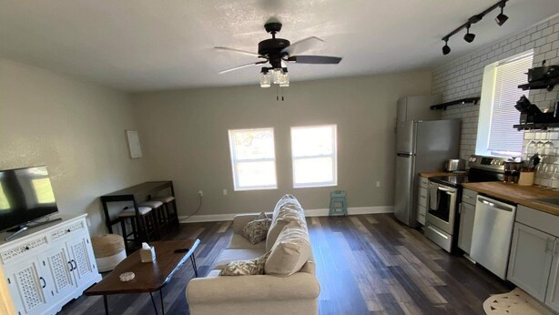 A spacious living room with a sofa, a dining table, and a kitchen area with a refrigerator, stove, and cabinets. - 1/1 Guesthouse 6mi from Beach for Perfect Getaway (Fort Walton Beach)