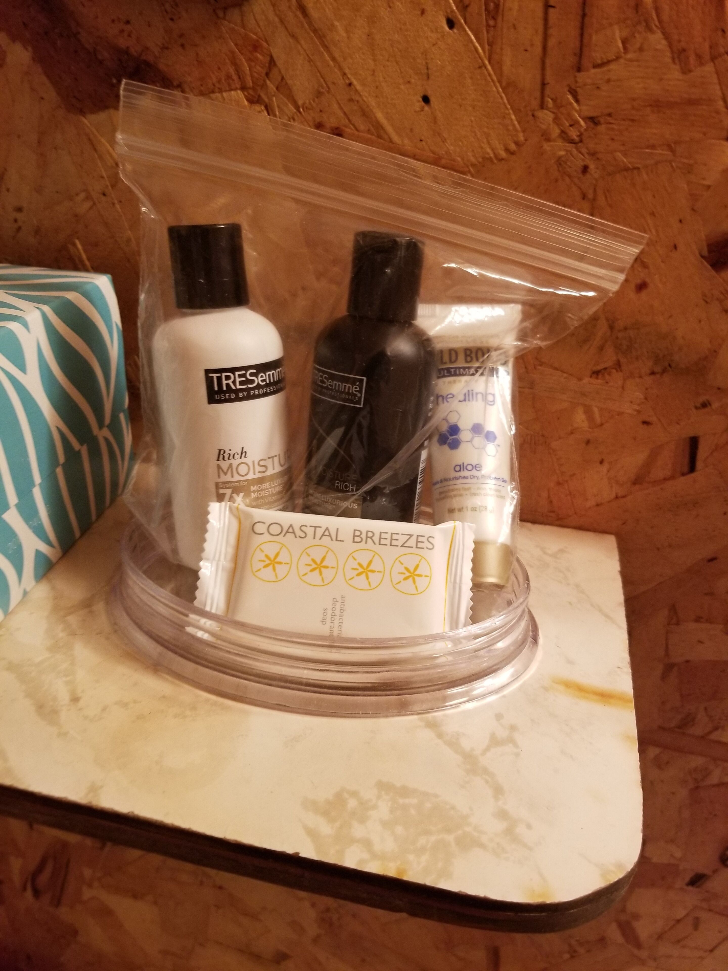 Een wastafelmeubel met een marmeren blad, een handdoek en toiletartikelen zoals een fles shampoo, een fles conditioner en een zeepstaafje.