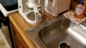 Una cocina con cafetera, tostadora y una botella de jabón de manos sobre la encimera.
