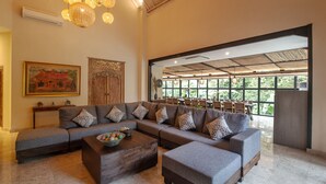 A spacious living area with a large sectional sofa, a coffee table, and a dining area with wooden chairs and tables. - Sunset Paradise Nusa Dua (Nusa Dua)