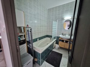 A bathroom with a bathtub, a sink, and a mirror.