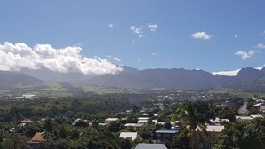 A town with a mountainous backdrop, houses, and scattered greenery. - T2 Escale sudiste, south of Reunion Island (Saint-Louis)