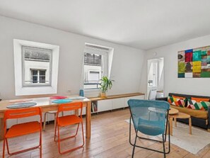 A modern kitchen with a dining area, wooden flooring, and a colorful abstract art piece on the wall. - Nice apartment in the heart of Paris by Weekome (Paris)