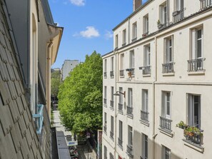 A narrow street with buildings on either side, featuring balconies with railings and potted plants. - Nice apartment in the heart of Paris by Weekome (Paris)
