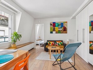 A modern living space with a dining area, a sofa with colorful cushions, and a wall art piece. - Nice apartment in the heart of Paris by Weekome (Paris)