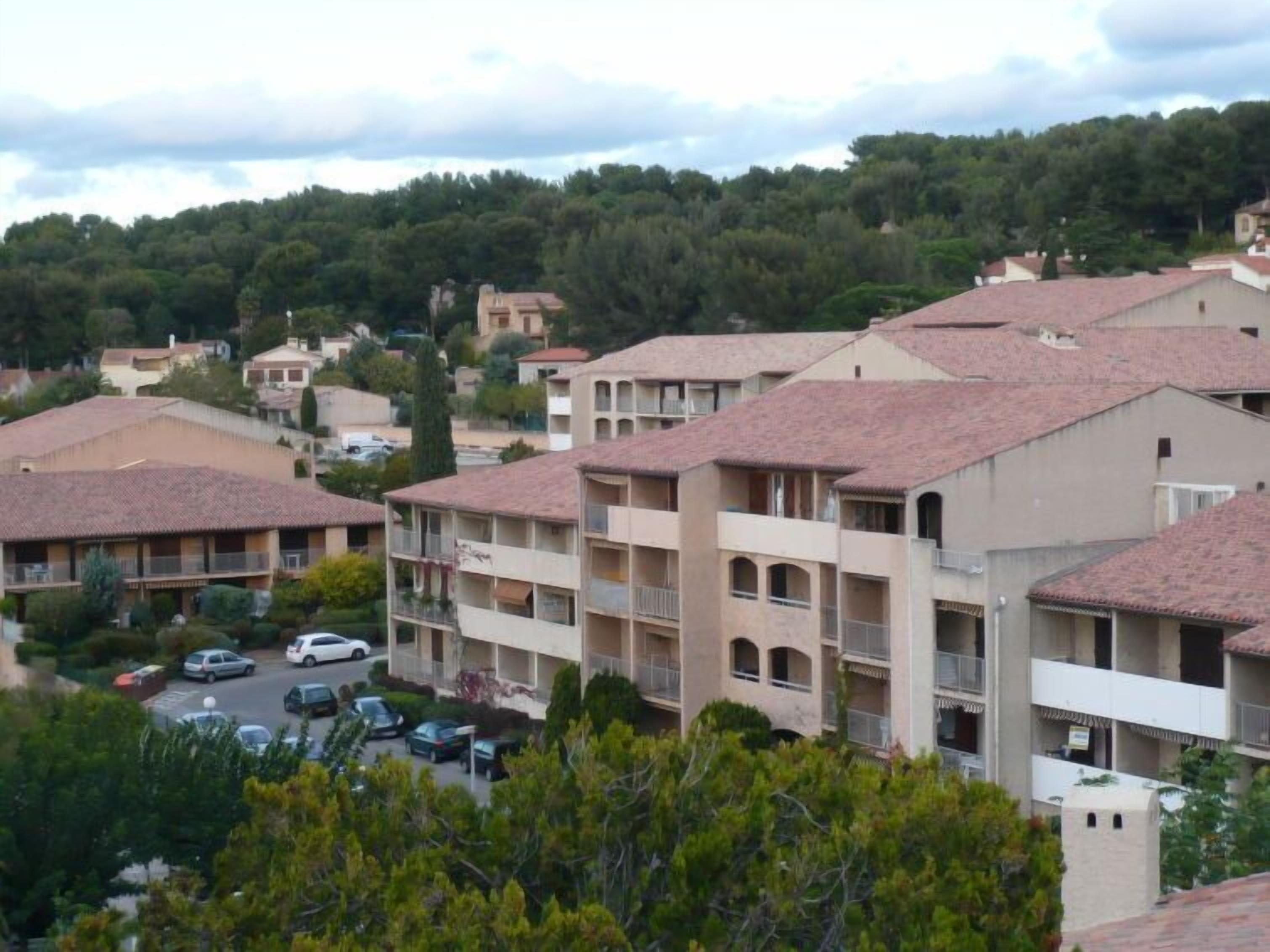 A residential area with multi-story buildings, some with balconies, and a parking lot with cars.