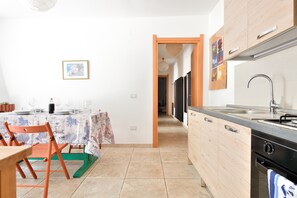 A kitchen with a dining area, a wooden cabinet, a sink, and a tiled floor.