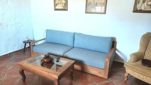 A living room with a sofa, a coffee table, a patterned armchair, and two framed pictures on the wall.