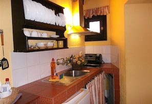 A kitchen with a countertop, a sink, a toaster, and a window with a curtain.