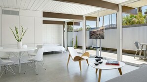 Een moderne hotelkamer met een bed, een zithoek met een tafel en stoelen, een bank, een televisie en uitzicht op de omgeving.