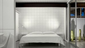 Een moderne slaapkamer met een bed, nachtkastjes en een glazen deur naar een balkon.