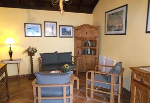 A cozy living room with a sofa, two armchairs, a wooden cabinet, and a lamp.