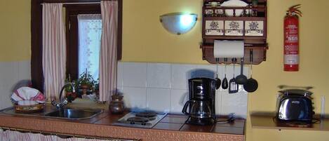 A kitchen with a sink, stove, coffee maker, and a fire extinguisher.