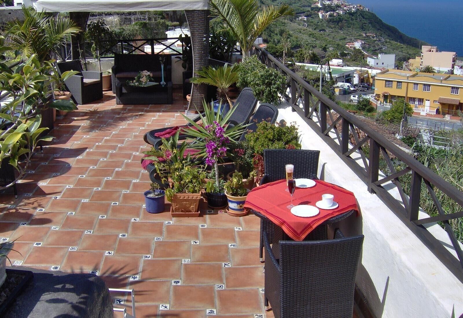 A terrace with outdoor seating, potted plants, and a table set for dining.