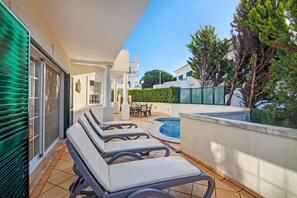 Una terraza en la azotea con sillones de descanso, una piscina y vistas de los alrededores.