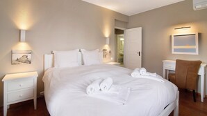 Een hotelkamer met een groot bed, nachtkastjes, een bureau en een stoel.
