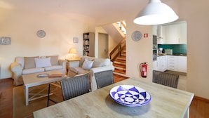 Una sala de estar con un sofá, una mesa de comedor y una cocina al fondo.
