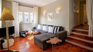 A modern living room with a sectional sofa, a wooden coffee table, a TV, and a staircase leading to an upper floor. - Villa 'Apple' with Sea View, Wi-Fi, and Air Conditioning (Vale do Lobo)