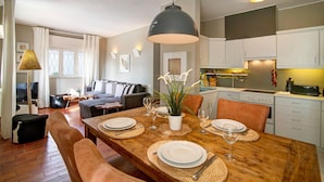 A dining area with a wooden table set for four, surrounded by chairs, a hanging light fixture, and a potted plant. - Villa 'Apple' with Sea View, Wi-Fi, and Air Conditioning (Vale do Lobo)