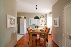 Ein Essbereich mit einem Holztisch, Stühlen, einer Hängelampe und einem Kühlschrank im Hintergrund.