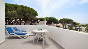 A balcony with two lounge chairs, a table with chairs, and a view of the sea. - Villa 'Harlequin' with Sea View, Wi-Fi and Air Conditioning (Vale do Lobo)