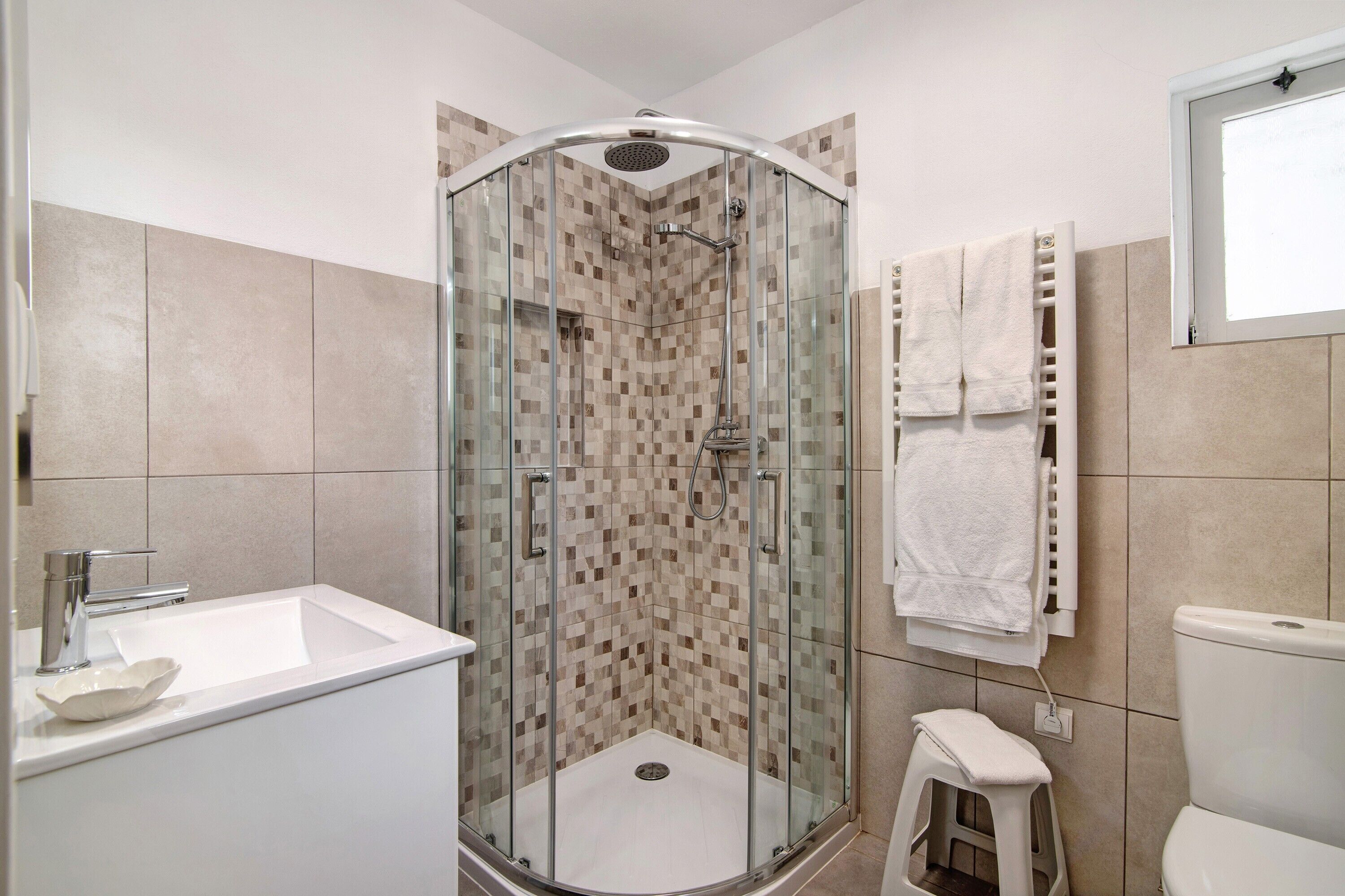 Un bagno moderno con doccia vetro, lavandino bianco e water.