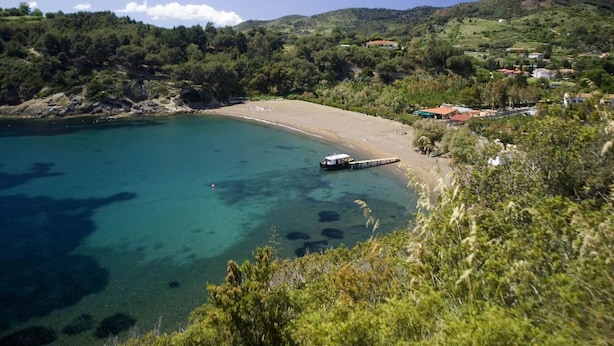 Una zona costiera con spiaggia, acqua limpida e una barca ormeggiata vicino alla riva.